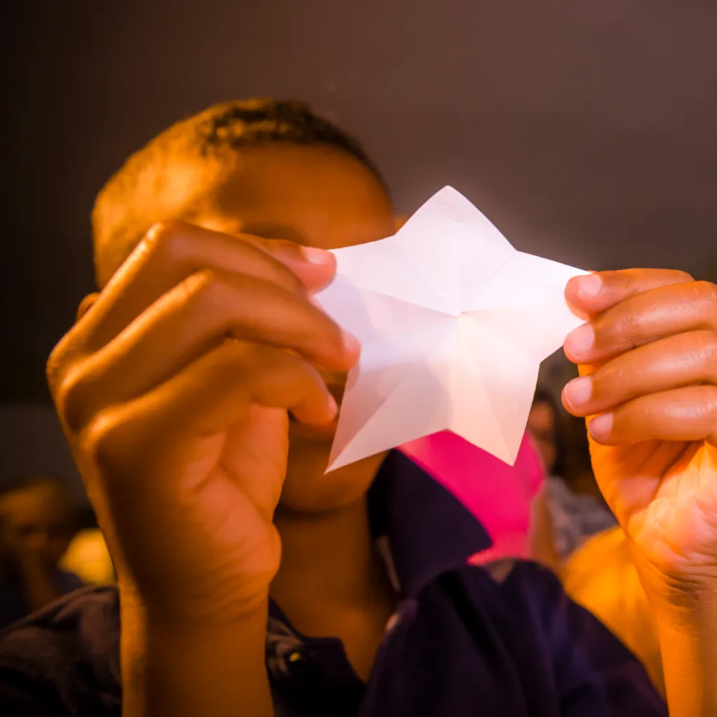 A child holds a paper star handcut by Betsy Ross