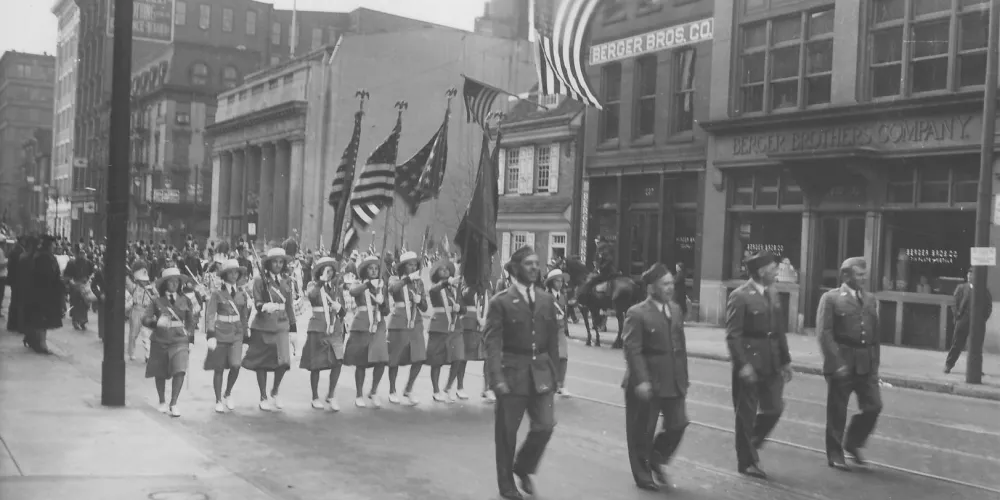 A parade marches in front of the Betsy Ross House in honor of flag day circa 1937