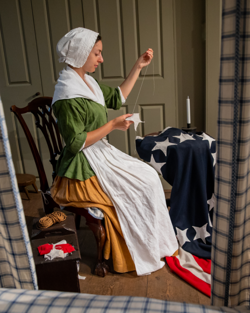 A History Maker portraying Betsy Ross sews the early US flag