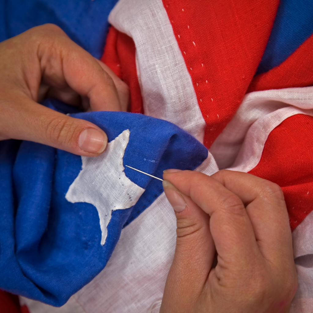 Close up of hands sewing a star to the American flag