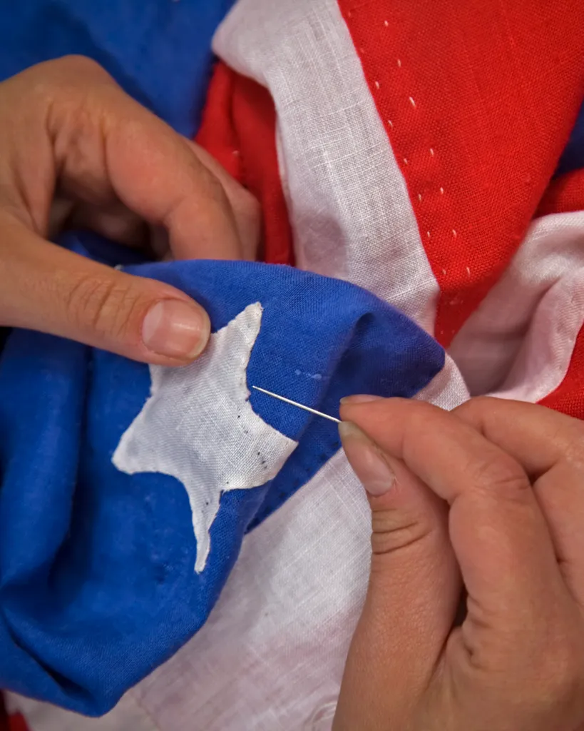 Close up of hands sewing a star to the American flag