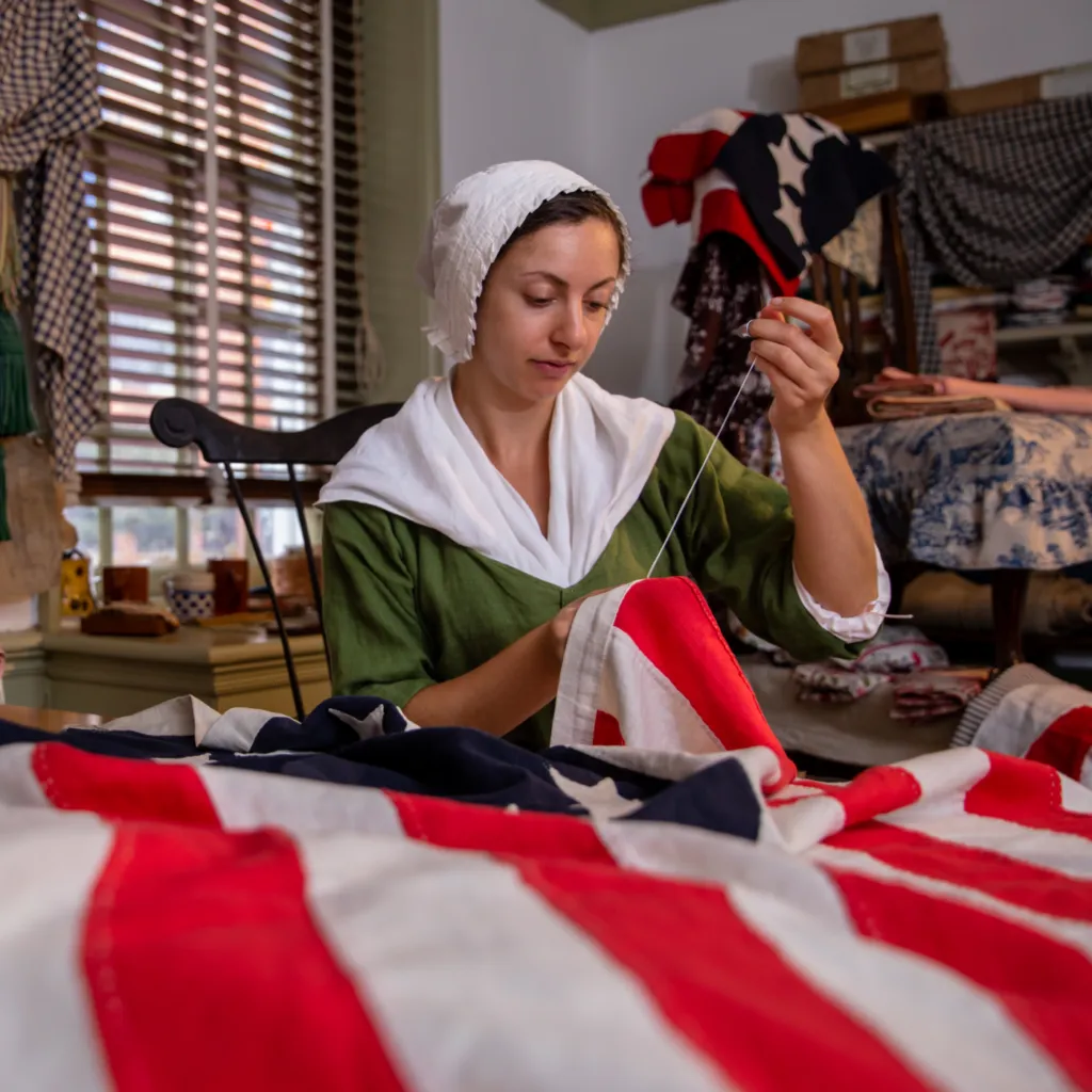 Betsy Ross sewing an American flag in her workshop