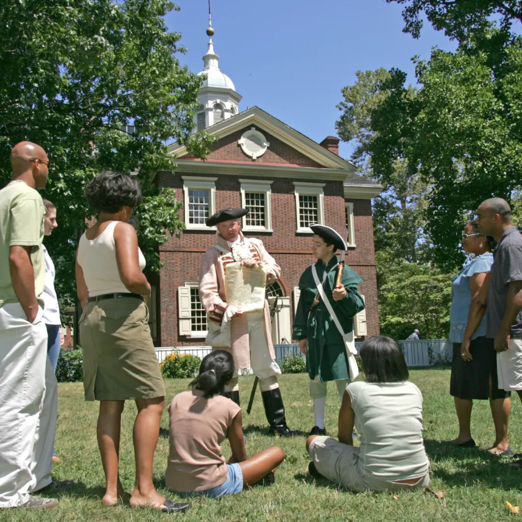 A History Maker in colonial costume speaks with a tour group outside of Carpenters' Hall