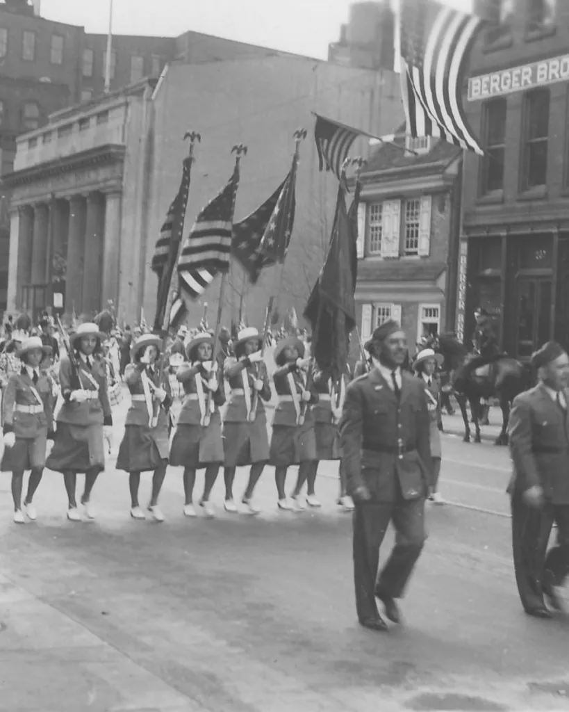 A parade marches in front of the Betsy Ross House in honor of flag day circa 1937