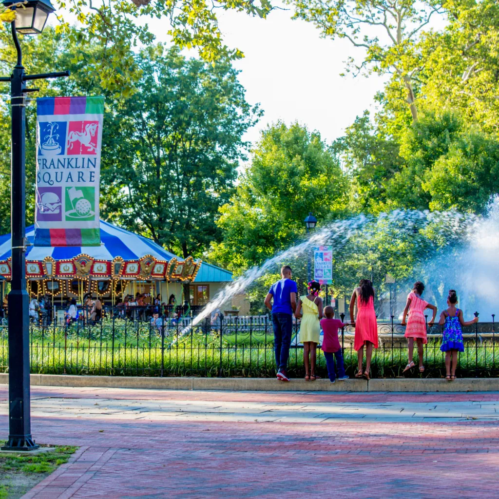 Children watching the fountain show in Franklin Square, with the Carousel off in the distance