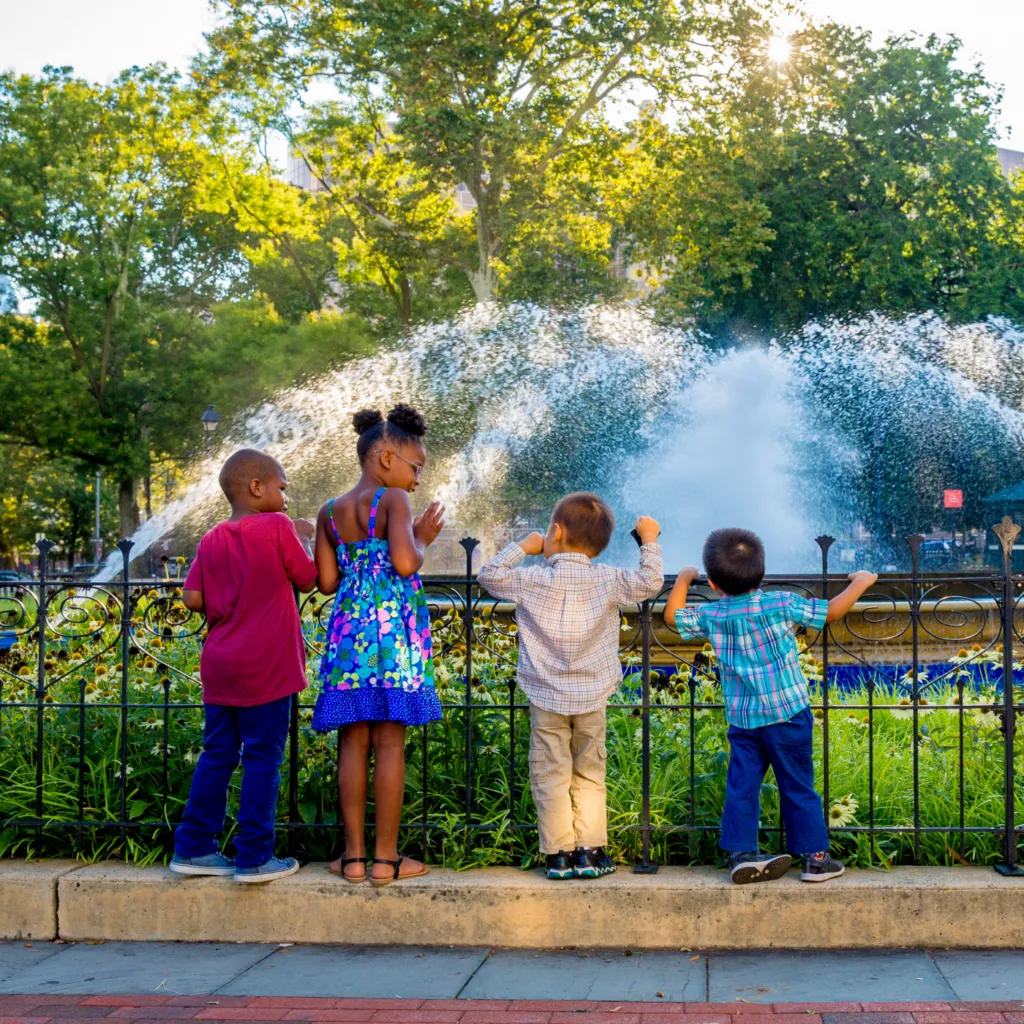 Young children lean over fence to watch the Franklin Square fountain show