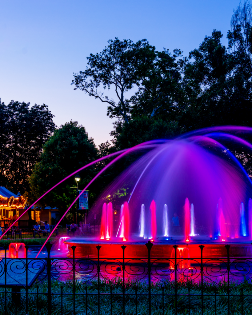 The Franklin Square fountain glowing pink and purple at night during the fountain show