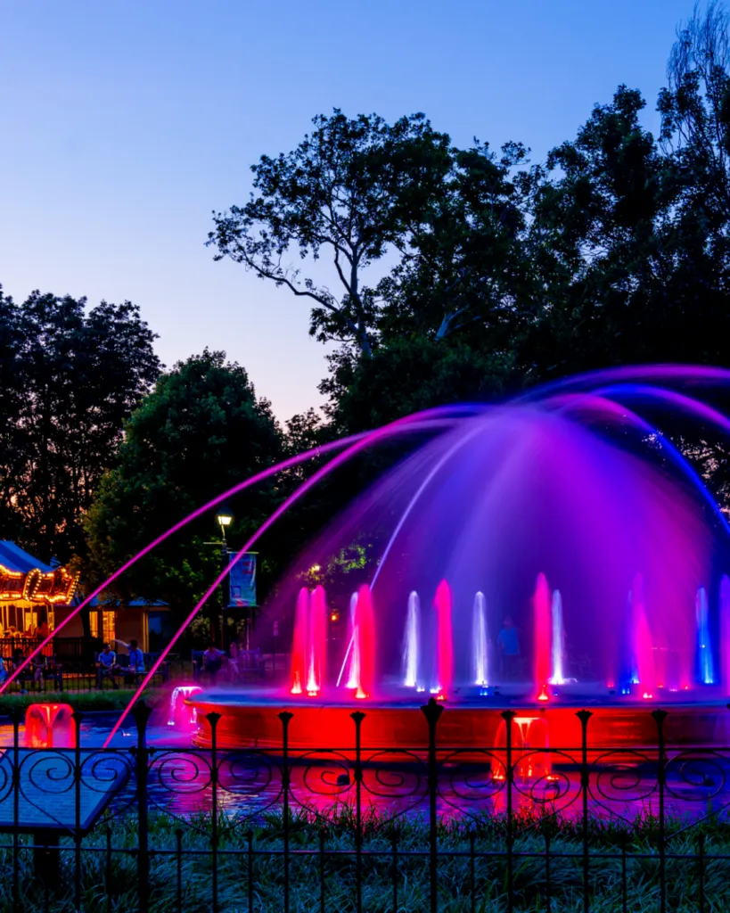 The Franklin Square fountain glowing pink and purple at night during the fountain show