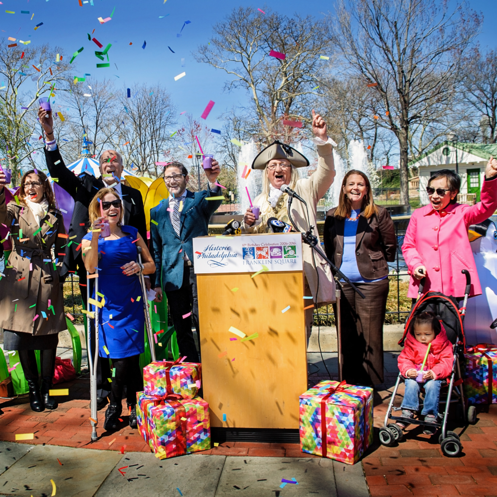 Un grupo de personas se para en un podio en celebración durante una conferencia de prensa de Franklin Square