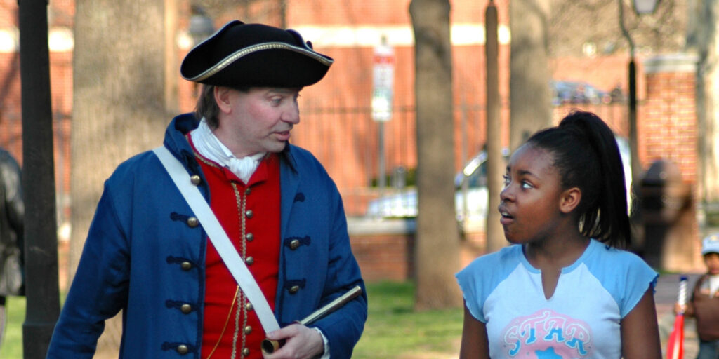 Colonial figure walks on a tour with guest.