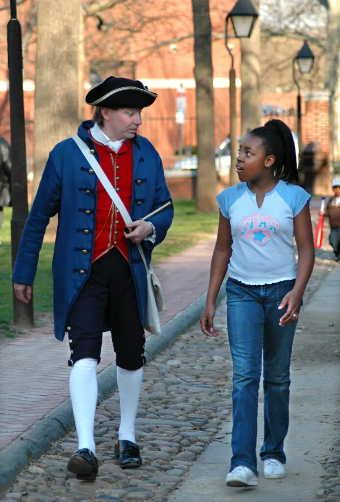 Colonial figure walks on a tour with guest.