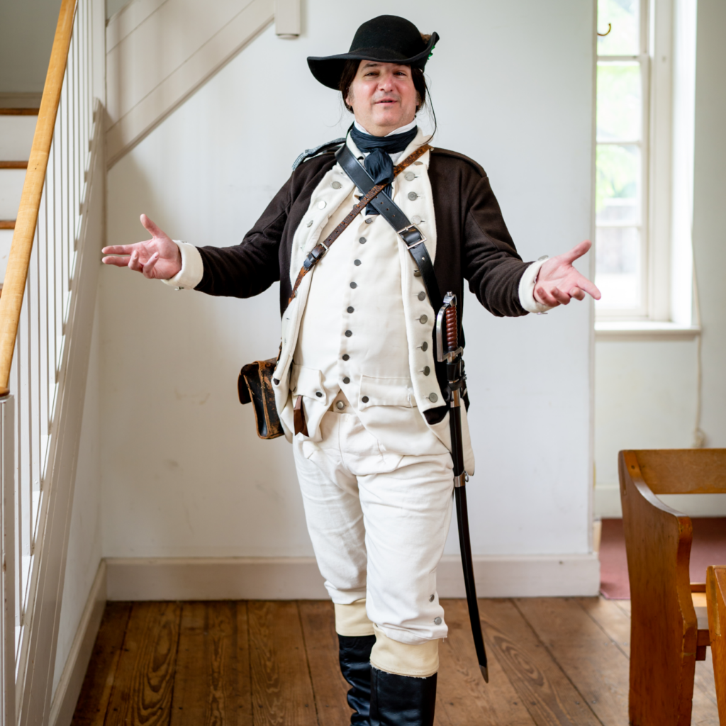 A History Maker portraying a colonial-era soldier poses for the camera with a sword