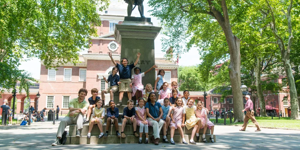 A group of children post for a photo with Historic Philadelphia, Inc. Storytellers as part of a tour