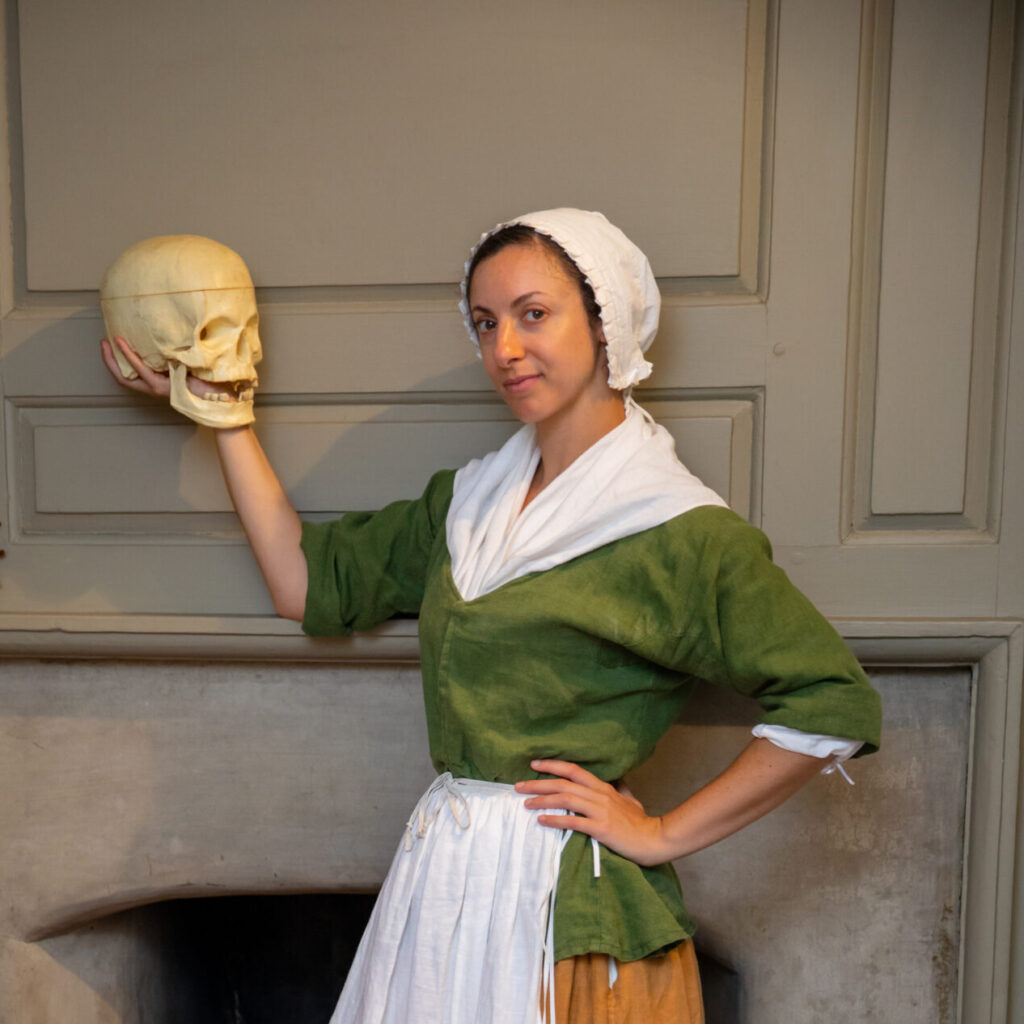 Photo of a Betsy Ross actress holding a fake human skull.